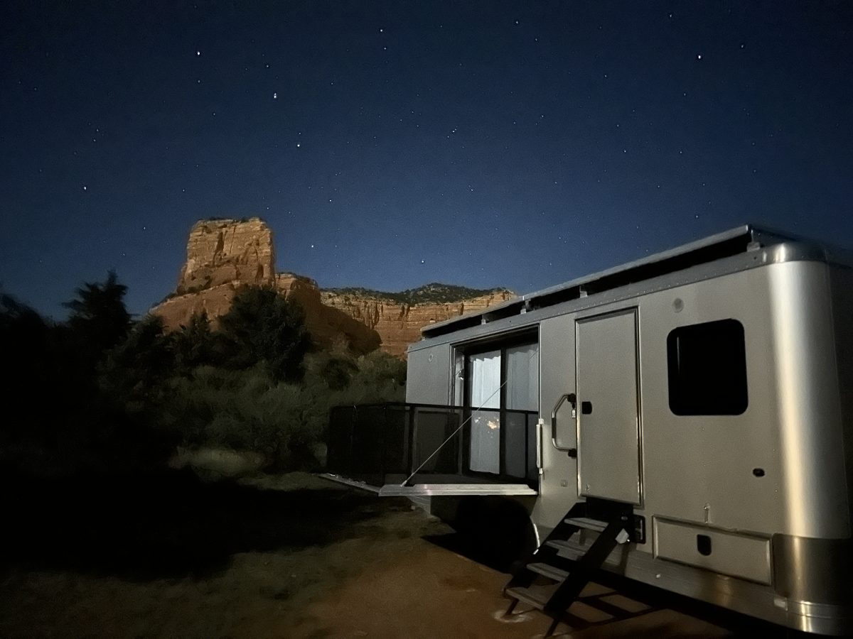 A Living Vehicle at night below a sandstone butte